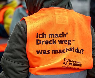 Kindergartenkinder in Warnweste "Ich mach Dreck weg" von hinten fotografiert
