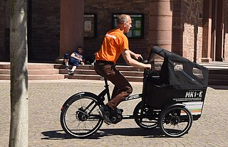 Ein Mann fährt auf einem Lastenfahrrad.