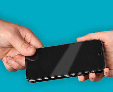 Eine Hand hält ein Smartphone und übergibt es einer anderen Hand