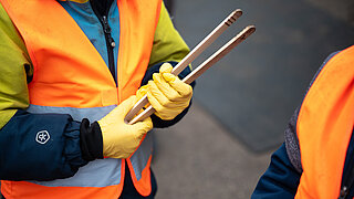 Eine Person hält eine kleine Greizange, bereit um Müll zu sammeln.