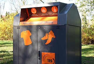 Ein Altkleider- und Schuhcontainer auf einer Wiese