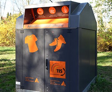 Ein Altkleider- und Schuhcontainer auf einer Wiese