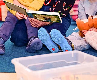 Kinder und Erzieher lesen gemeinsam ein Buch