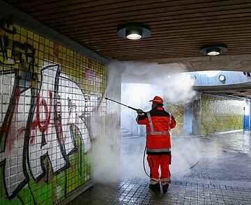 Mitarbeiter des TSK reinigt die Wände einer Unterführung