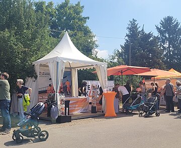 Infostand bei schönem Wetter mit verschieden kleinen Zelten und Besuchern