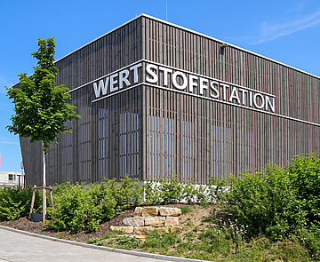 Ein modernes Gebäude auf dem mit großen Lettern Werstoffstation steht.